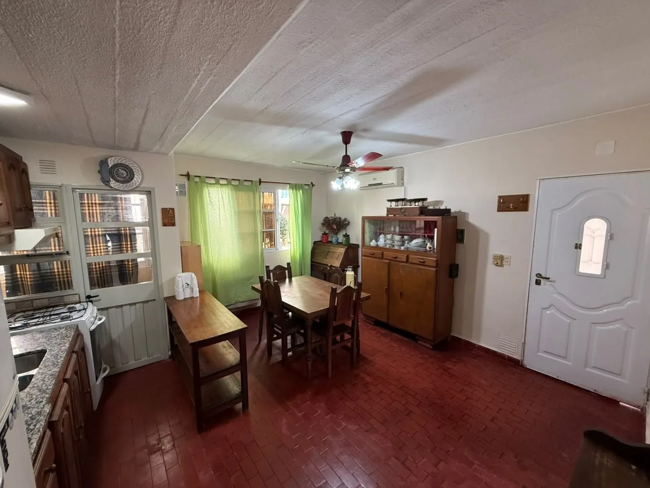 El comedor hacia la puerta de entrada, con la cocina a la izquierda y la ventana al fondo