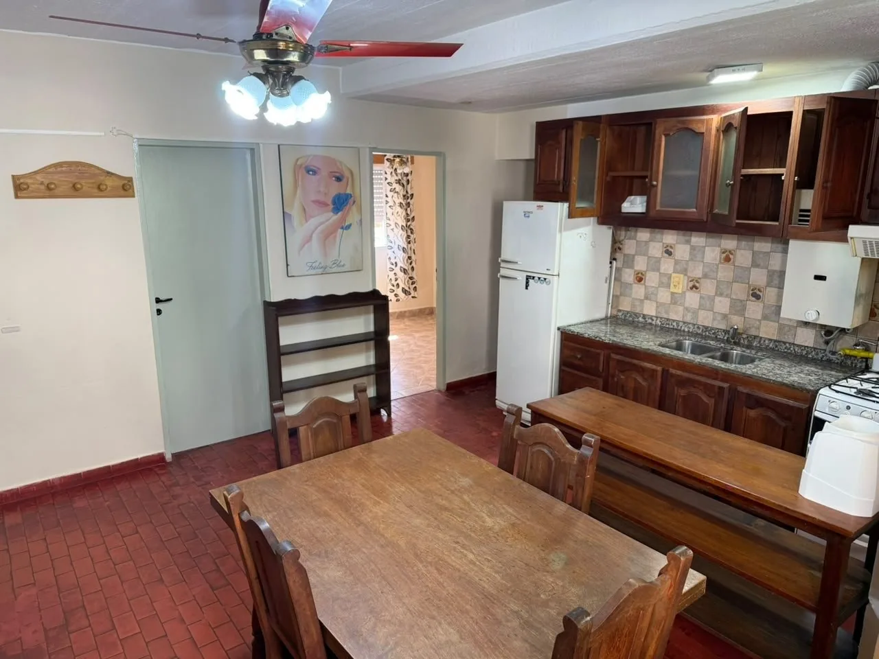 Desde la mesa, el paso a los dormitorios y la cocina con heladera, alacenas y calefón