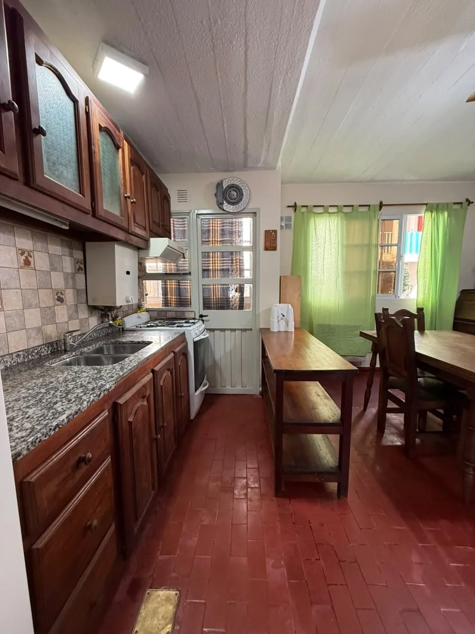 La cocina: mesada de granito con bacha doble, alacenas de madera arriba y abajo, cocina con horno y campana
