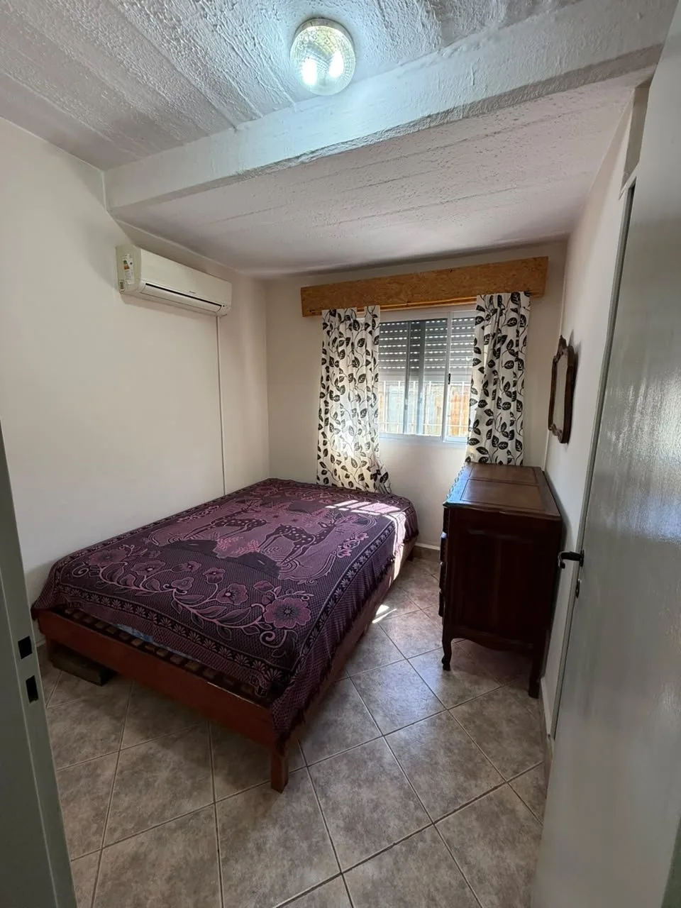 El primer dormitorio desde la puerta, con aire acondicionado y ventana con persiana