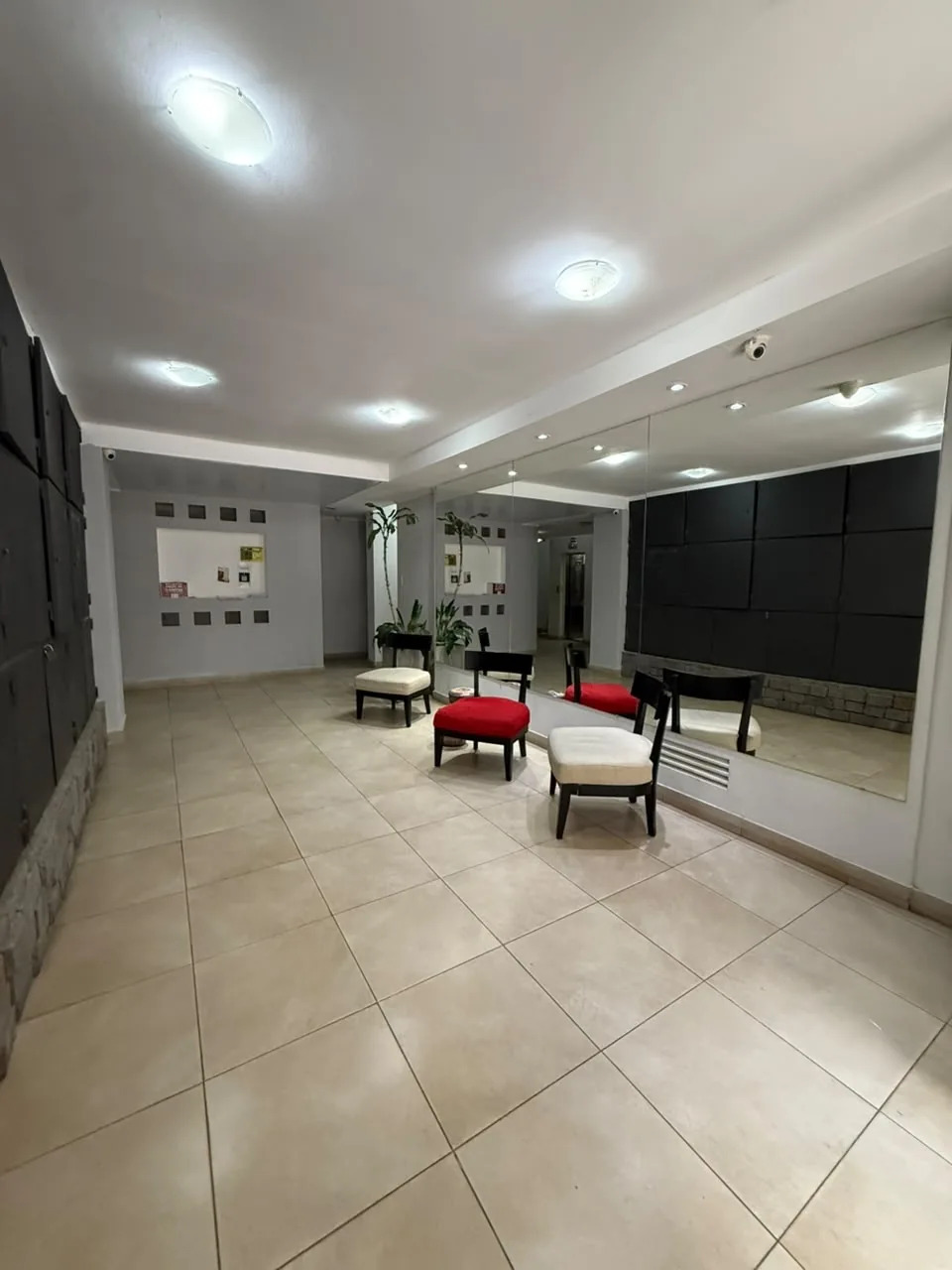 El hall de entrada, amplio y luminoso, con espejos, sillones y cámaras de seguridad