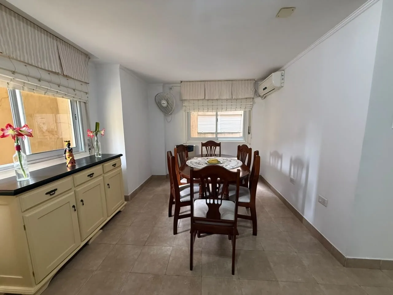 El comedor, con aire acondicionado split, ventilador de pared y ventanas a ambos lados