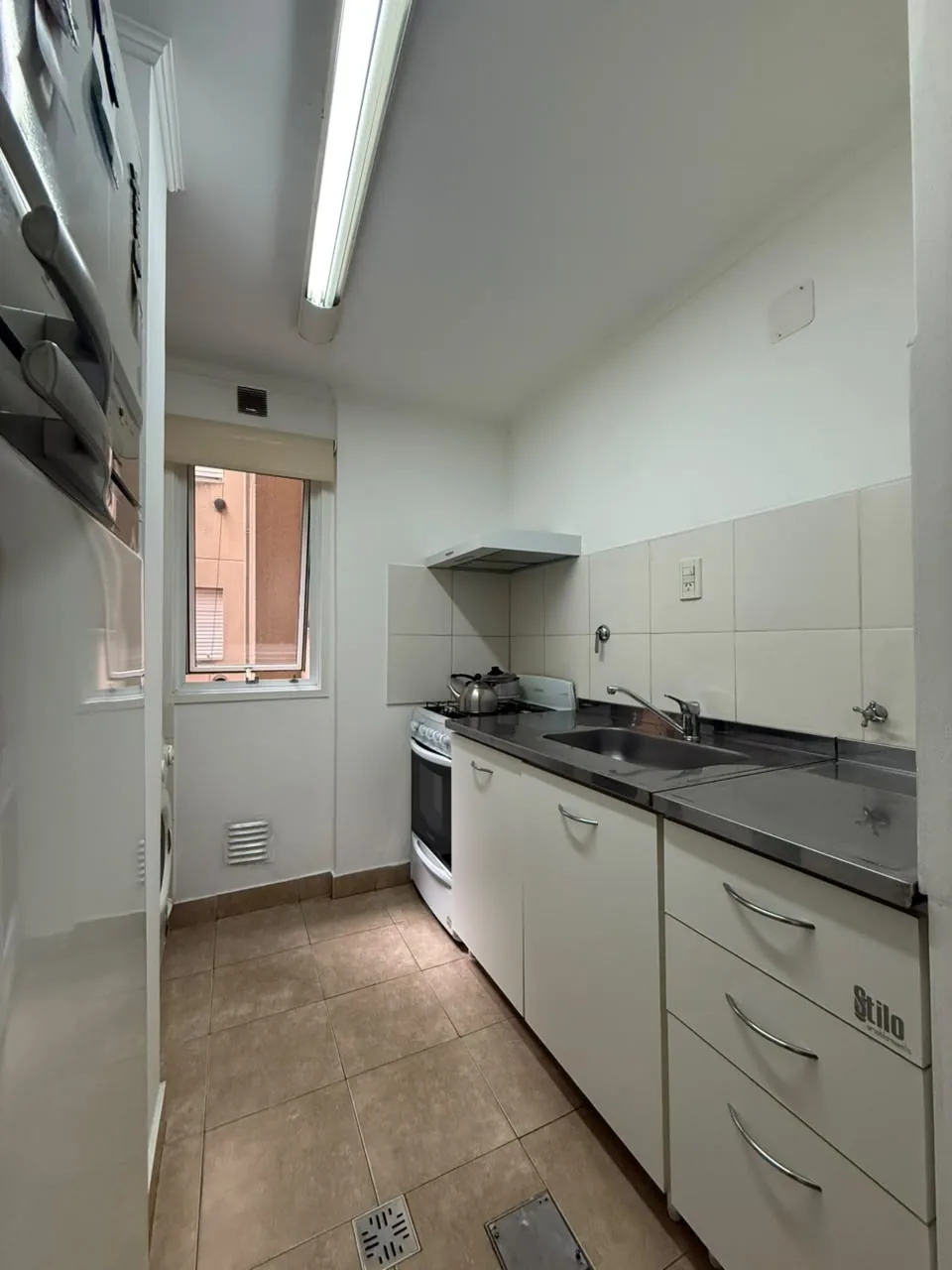 La cocina semisectorizada, con mesada de acero inoxidable, bajo mesada con cajonera y ventana