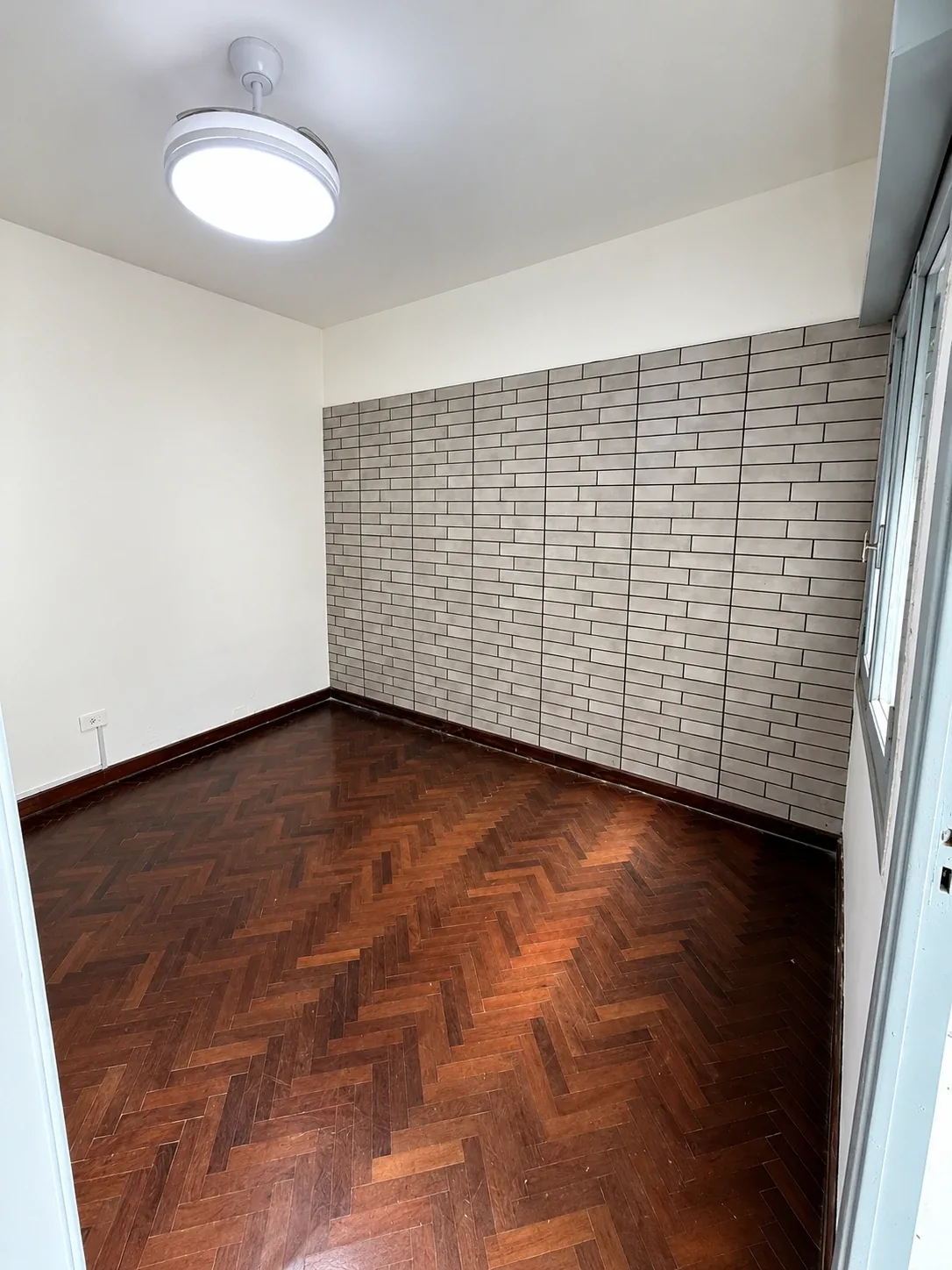 El mismo dormitorio, con piso de parquet y ventana con persiana