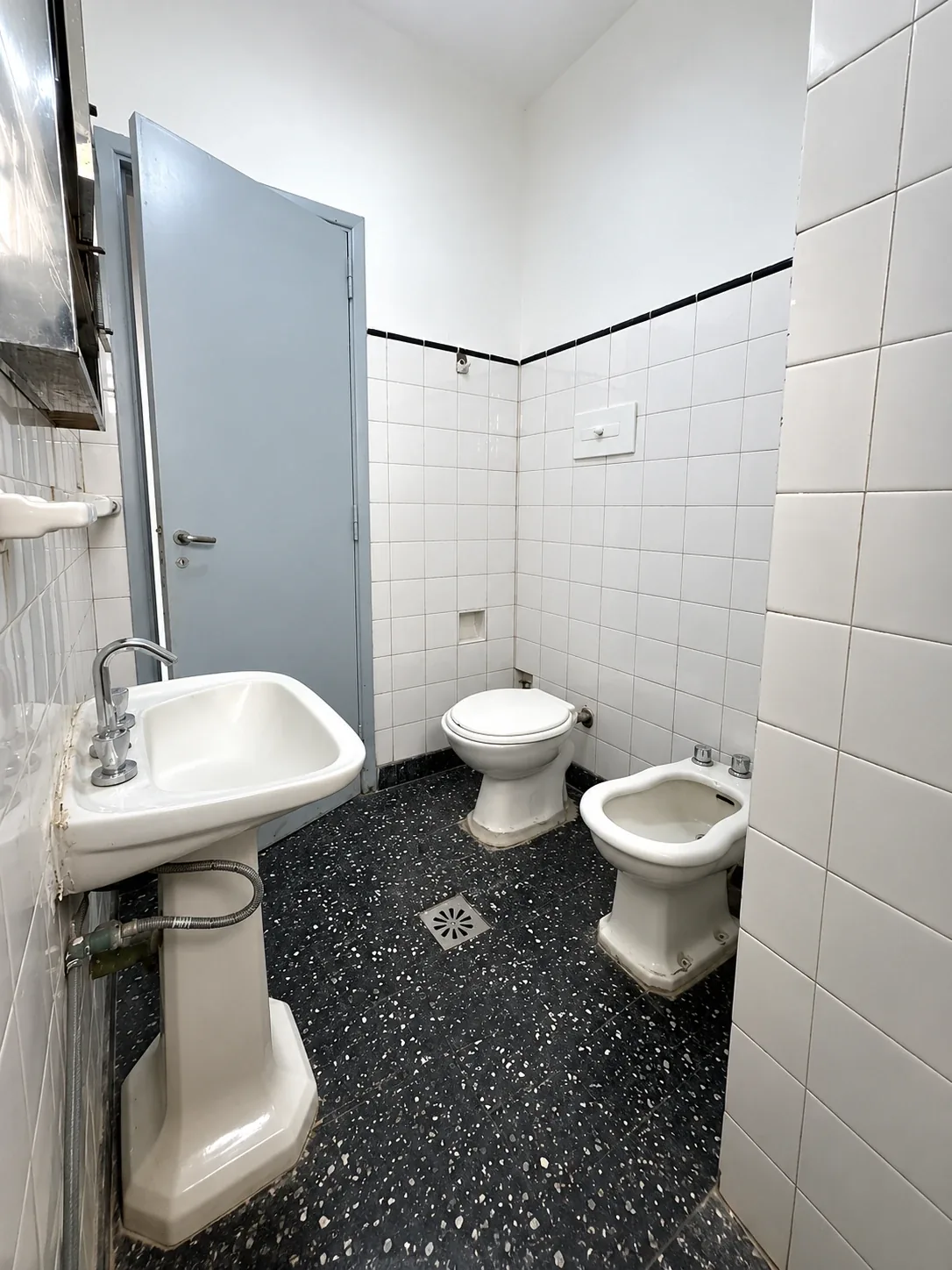 El baño, con inodoro, bidet y piso granítico