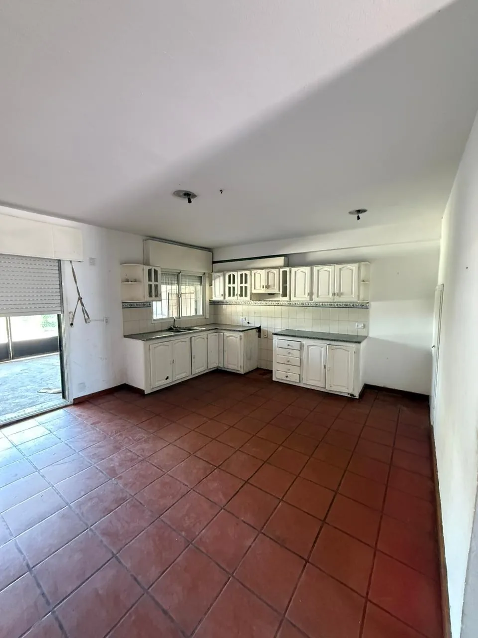 La cocina, amplia, con bajo mesadas, alacenas y salida al fondo