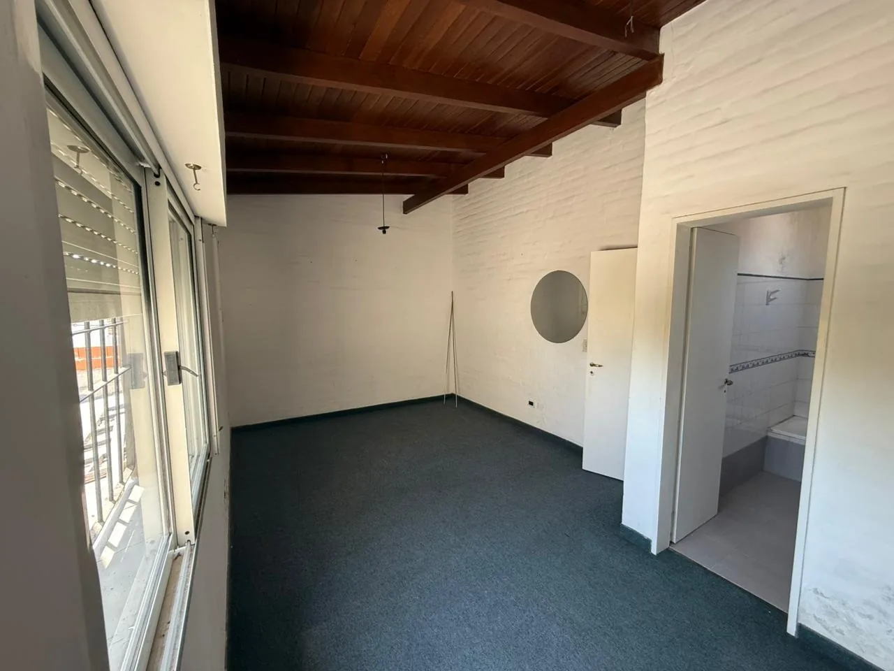 Dormitorio en suite, con techo de madera y su baño