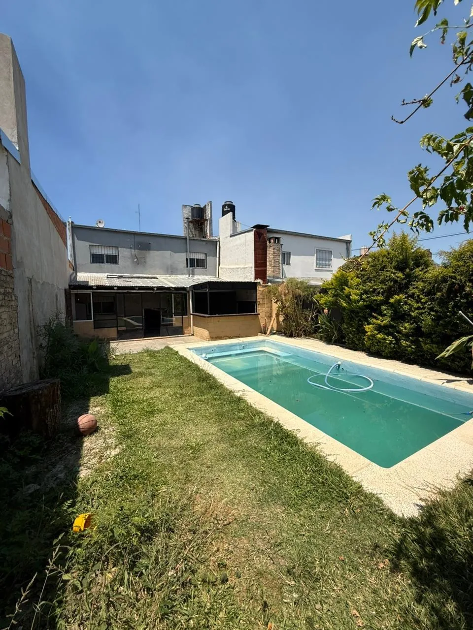El patio con césped y la pileta, con la casa al fondo