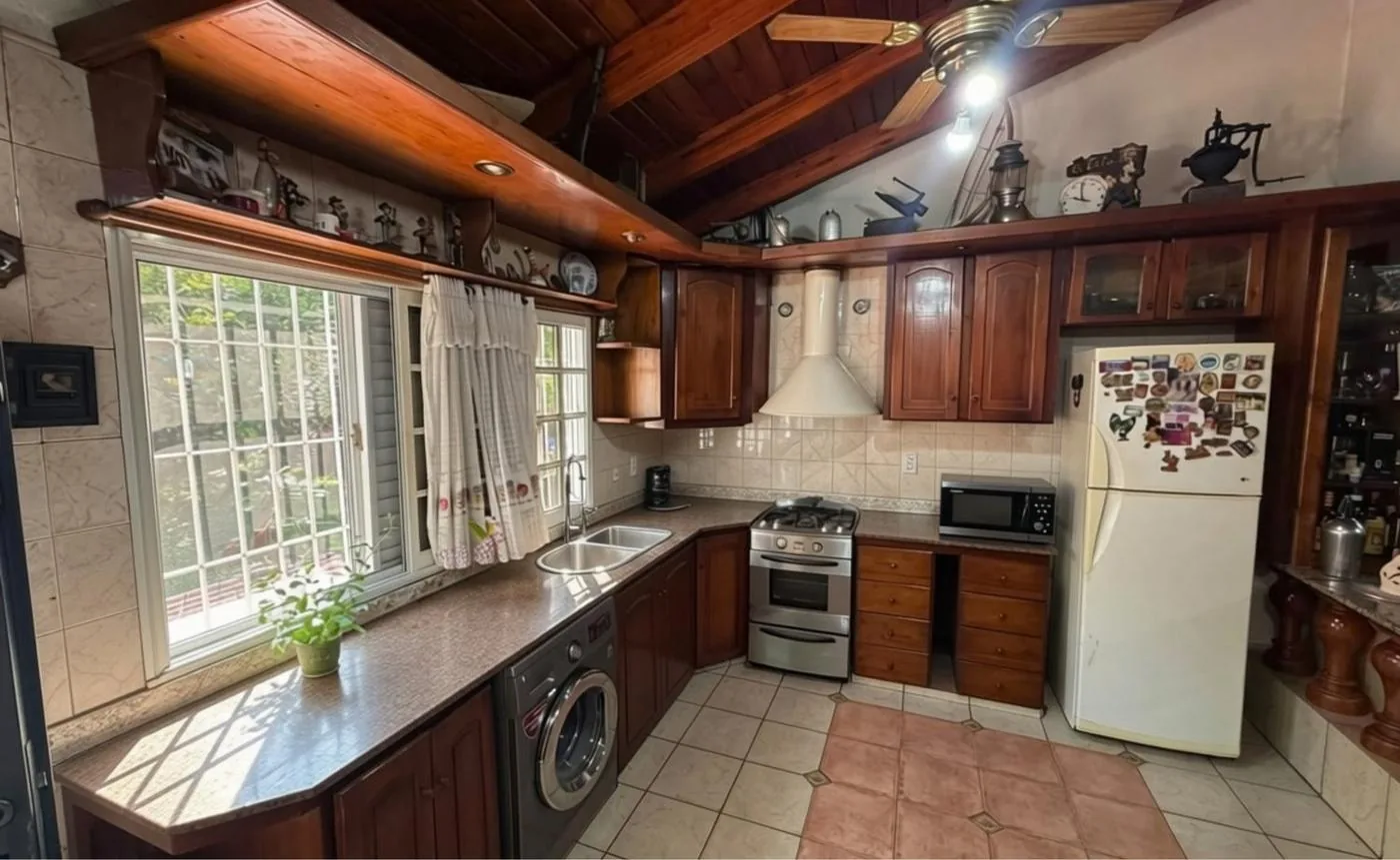 Cocina con muebles de madera maciza, mesada de granito en "L", campana y lavarropas incorporado