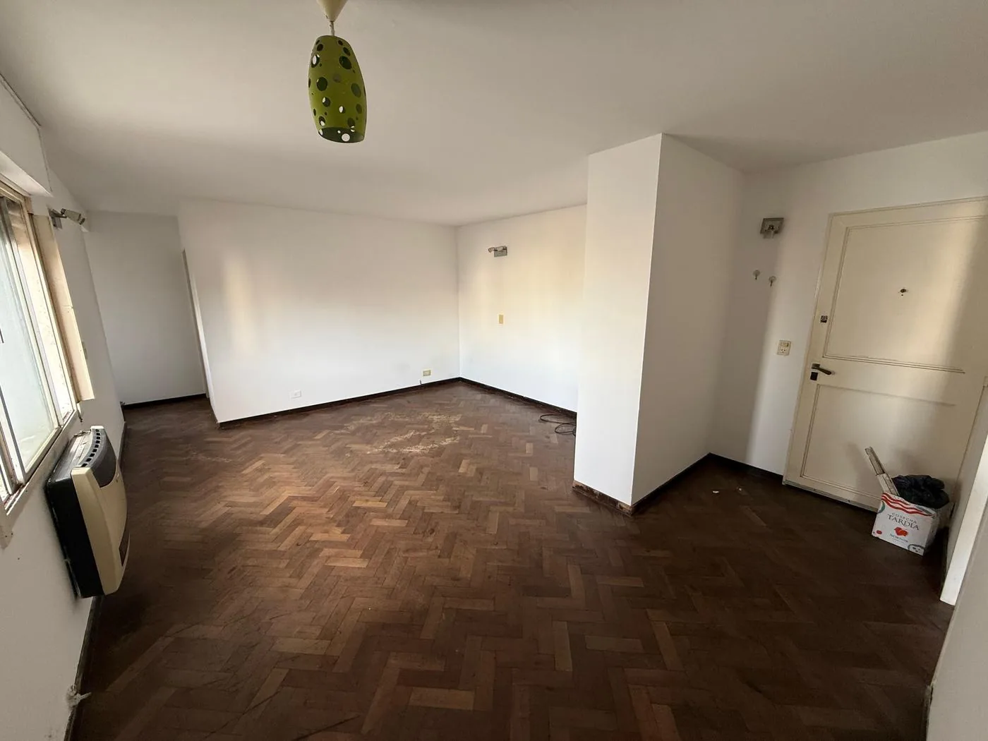 El living comedor desde la puerta de entrada, con piso de parquet en espina de pescado y calefactor a gas
