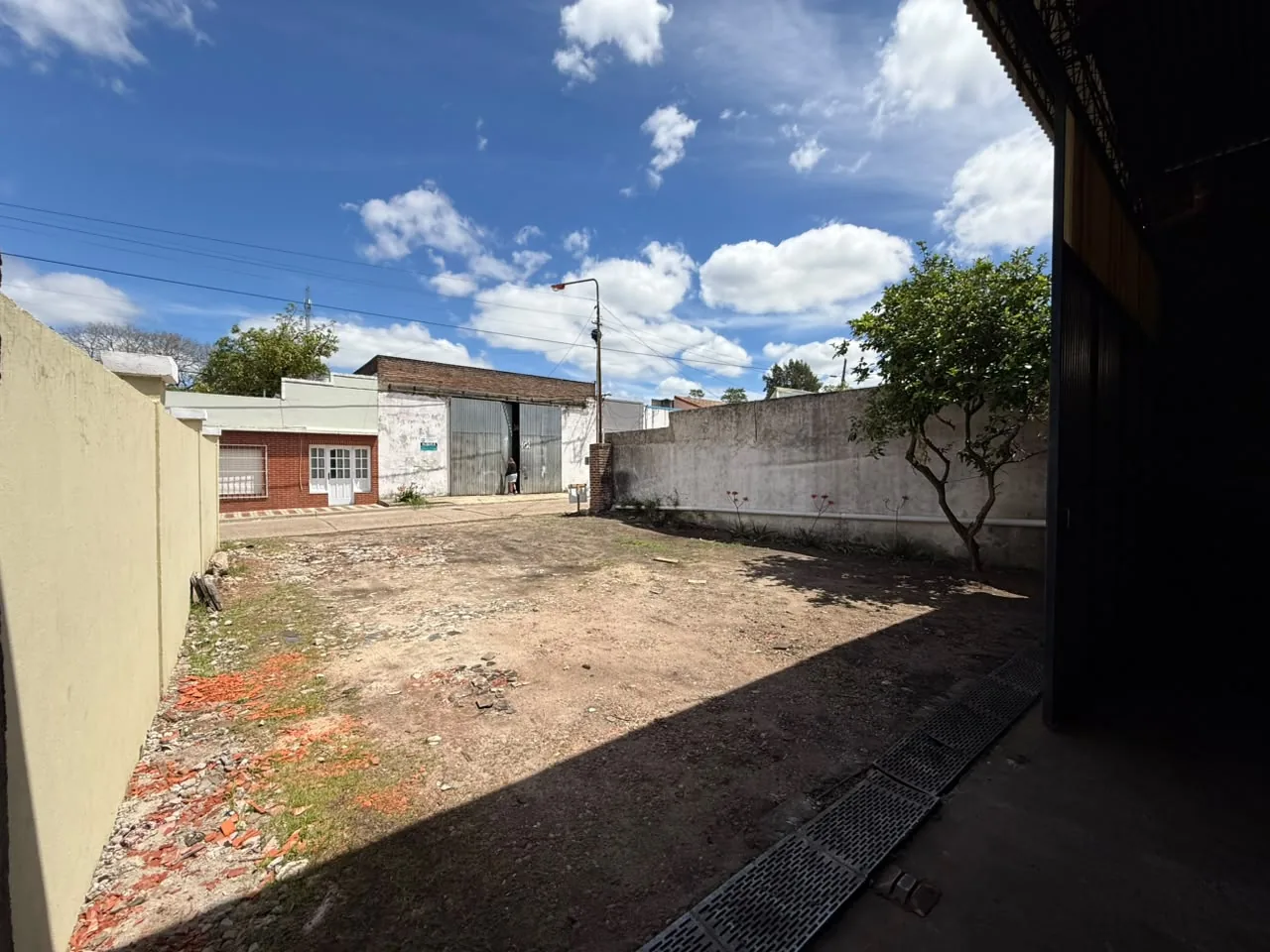 Desde la nave hacia la calle: el patio delantero y la rejilla de desagüe junto al portón