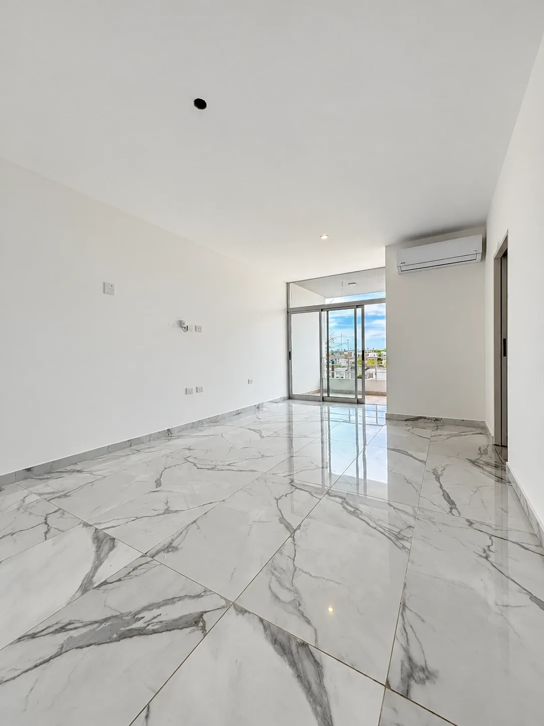 El living comedor hacia el balcón, con aire acondicionado y ventanal de piso a techo