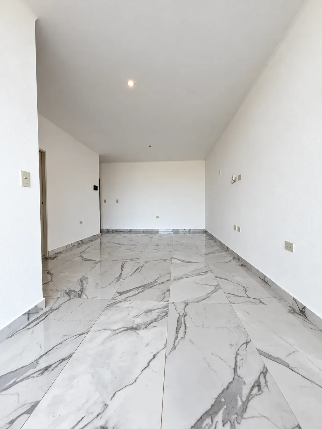 El living comedor de punta a punta, con pisos símil mármol