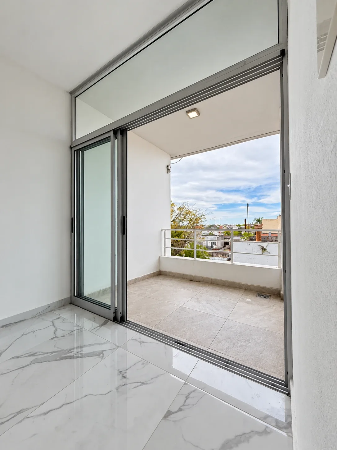 La salida al balcón, con ventanal corredizo de aluminio y paño fijo superior