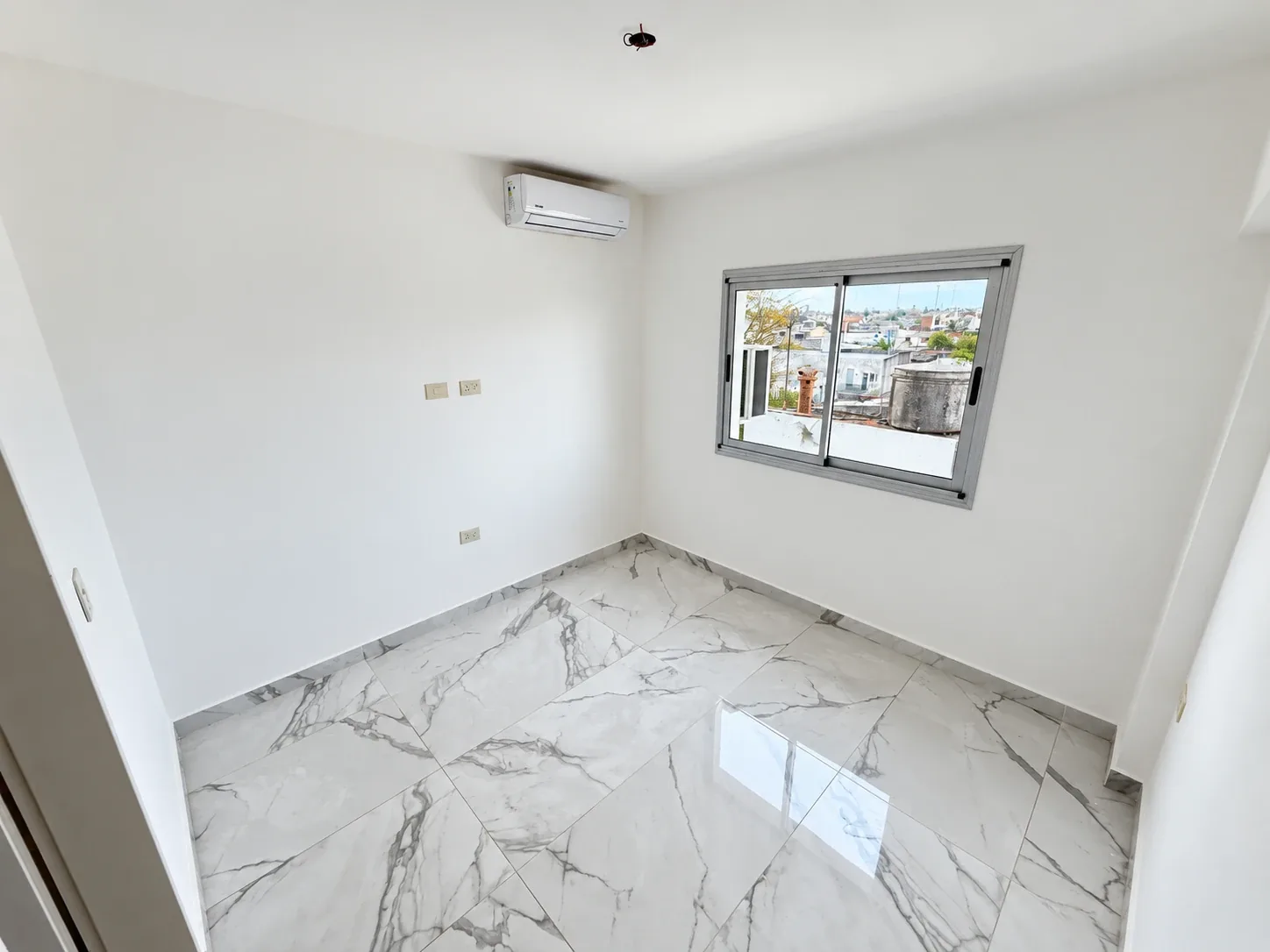 El dormitorio, con aire acondicionado y ventana con vista a la ciudad