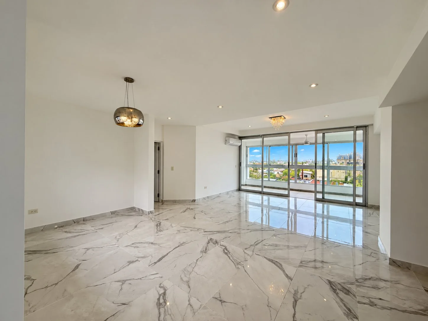 Hacia el balcón cerrado, con ventanales de piso a techo y vista a la ciudad