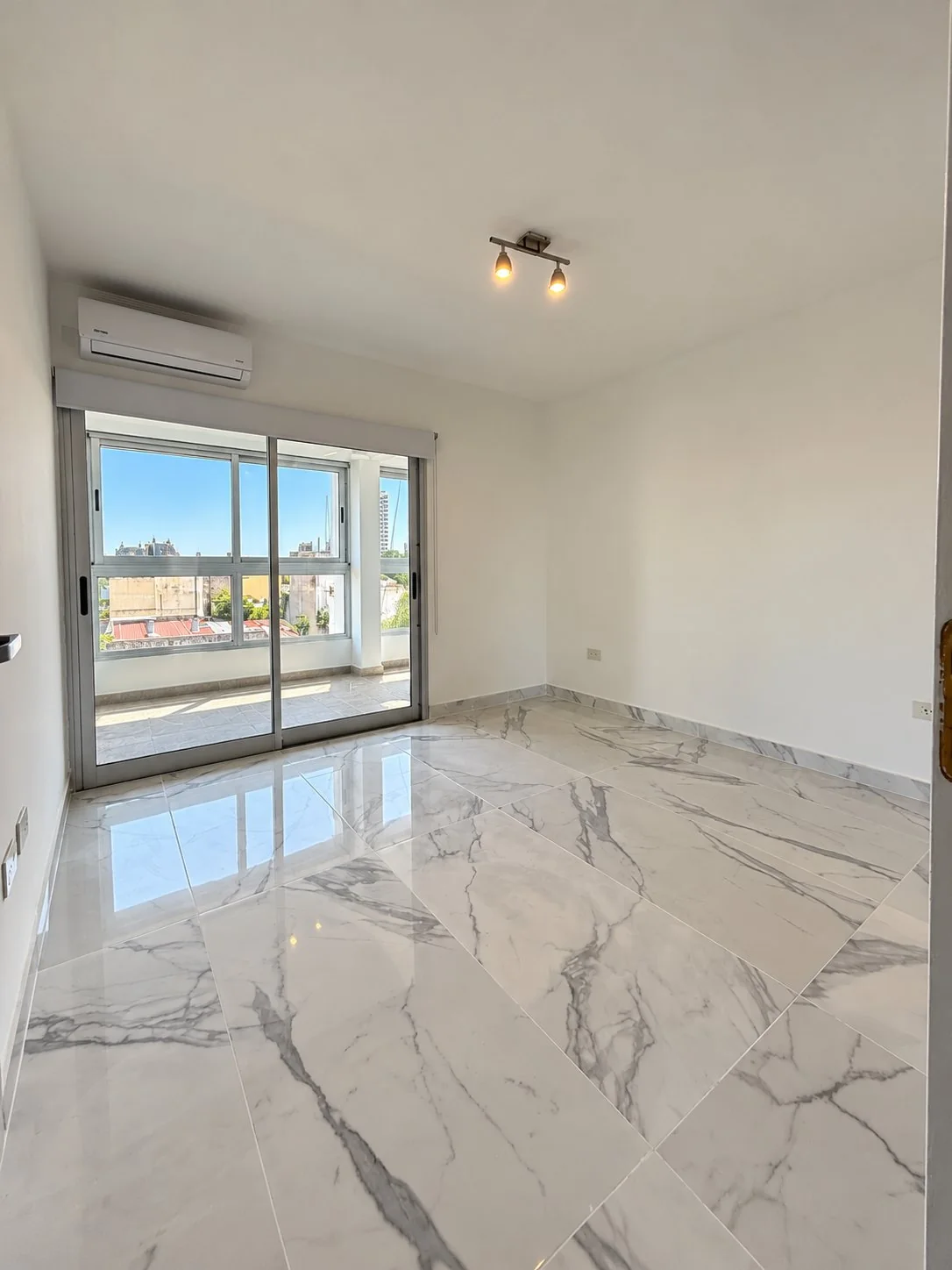 Dormitorio con piso símil mármol, aire acondicionado y salida al balcón cerrado