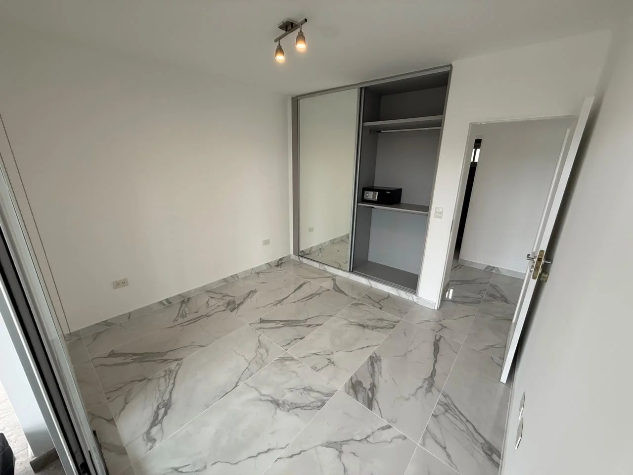 El mismo dormitorio, con placard de puerta espejada y caja fuerte