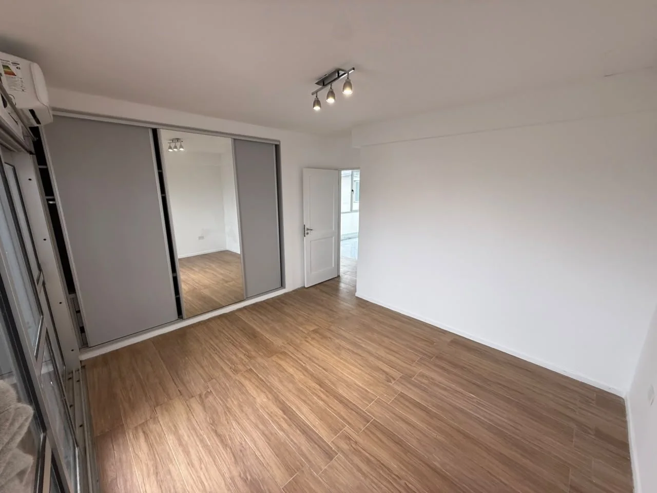 Dormitorio con placard de tres puertas corredizas, una espejada, y aire acondicionado