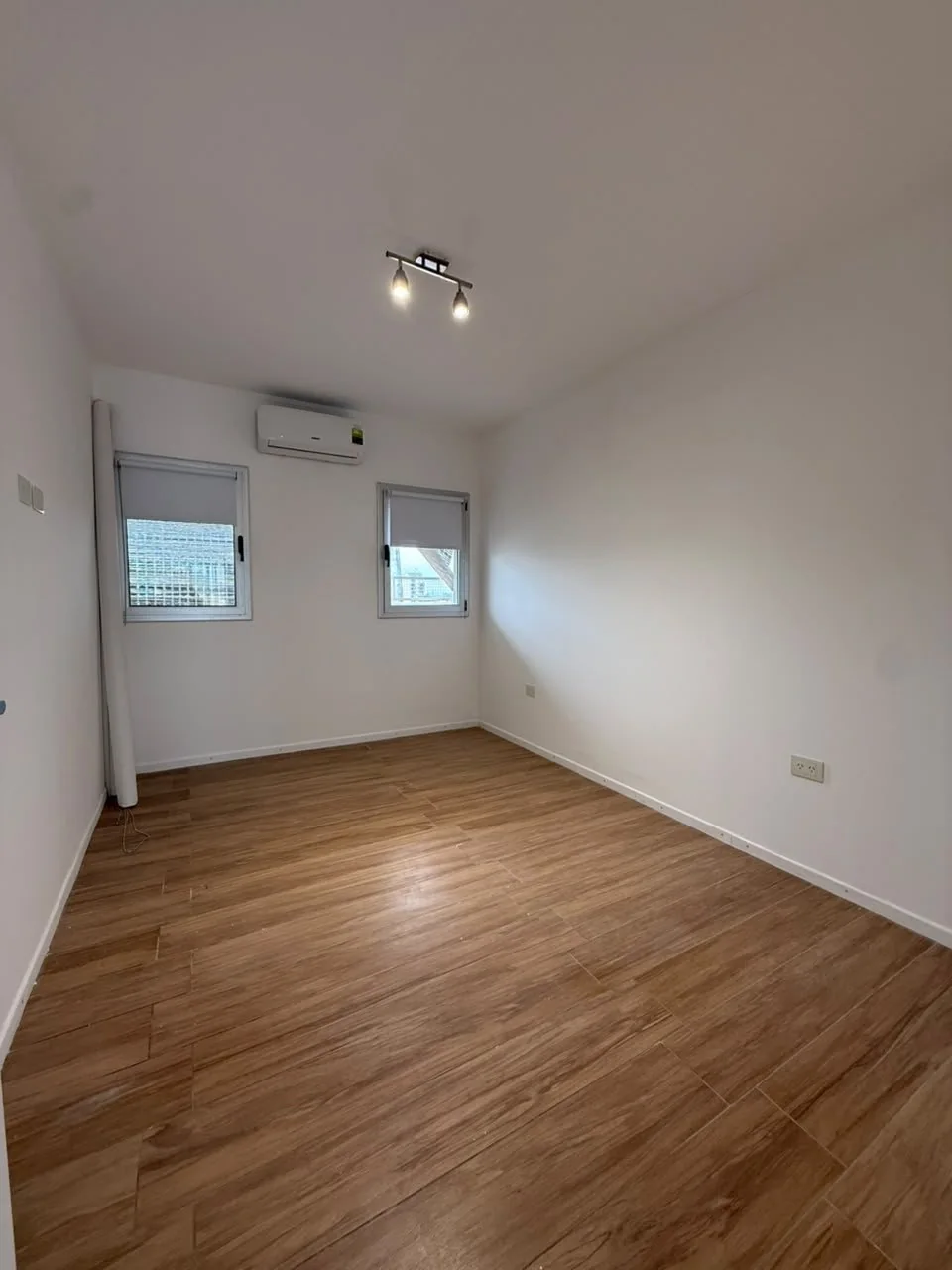 Dormitorio con dos ventanas y aire acondicionado