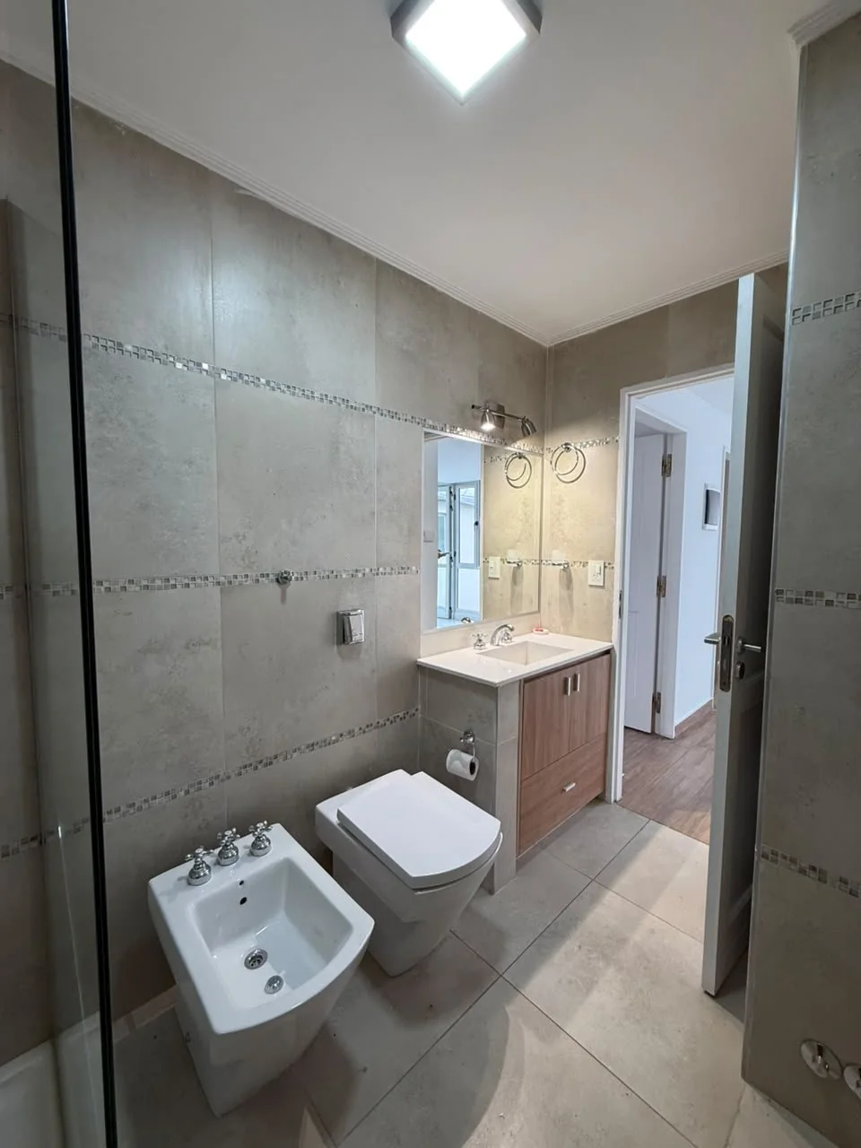 El mismo baño, con revestimiento porcelanato y guardas de mosaico