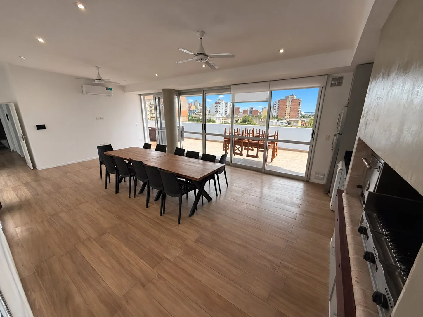 El quincho, de uso exclusivo y dentro del departamento: mesa para doce, parrillas y salida al balcón