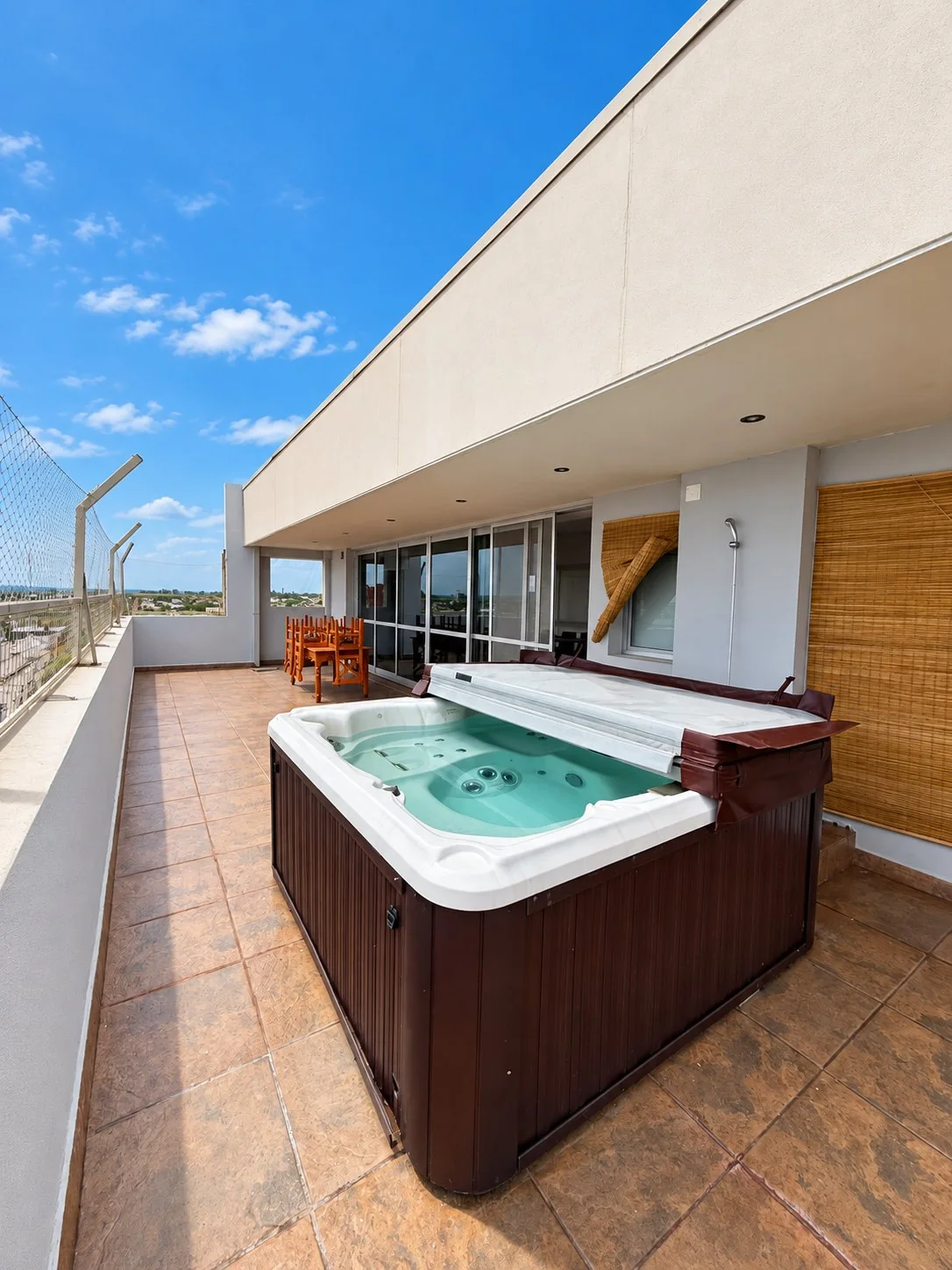 El jacuzzi con el cobertor abierto, la mesa exterior y la salida del quincho al fondo