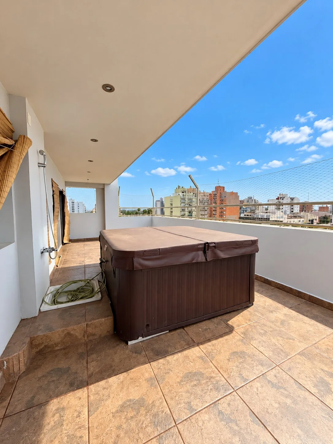 El jacuzzi bajo el alero, con ducha exterior y vista abierta a la ciudad