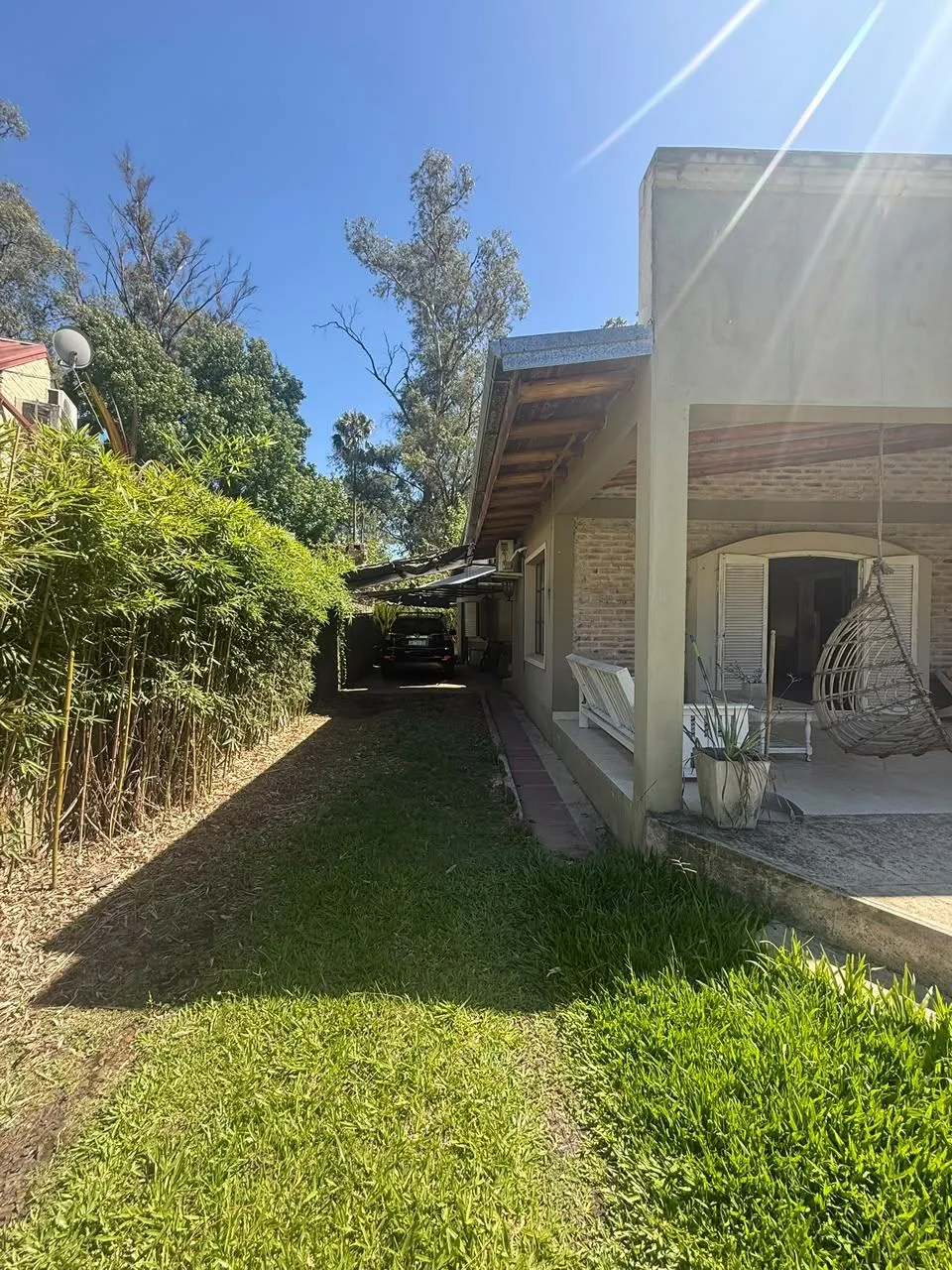 El lateral parquizado, con cerco de bambú y el garage semicubierto al fondo