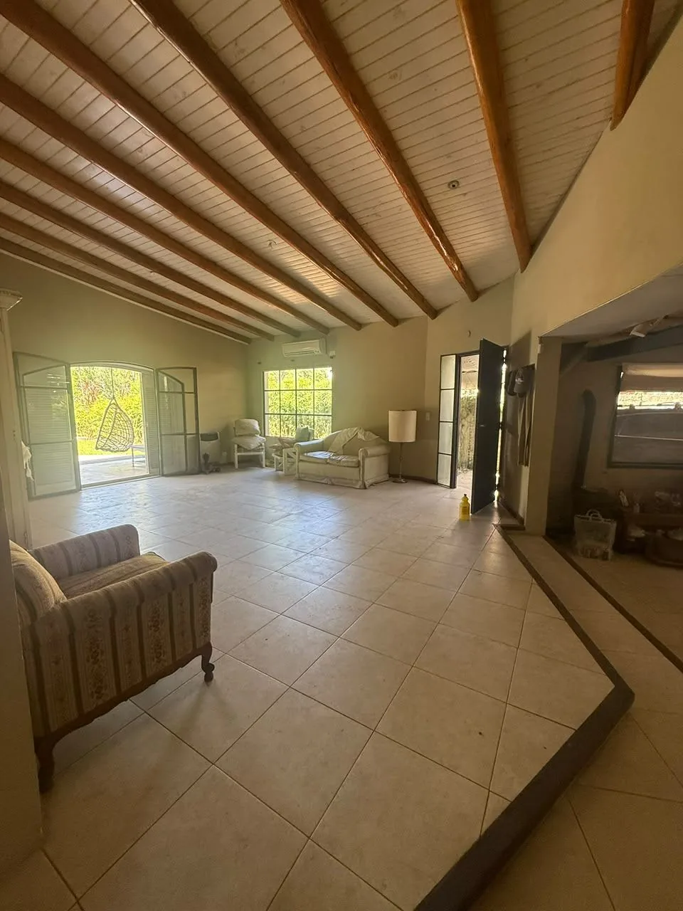 El living, amplio y luminoso, con techo de madera a la vista, aire acondicionado y salida directa a la galería y la pileta