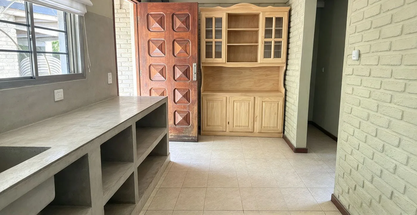 Otra vista de la cocina, con aparador de madera y salida al exterior