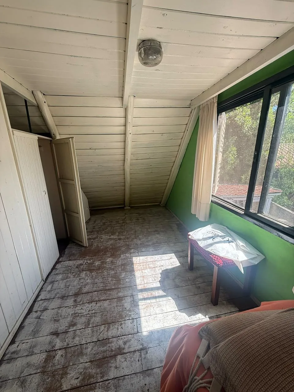 El mismo dormitorio hacia el placard, con techo a dos aguas y piso de madera