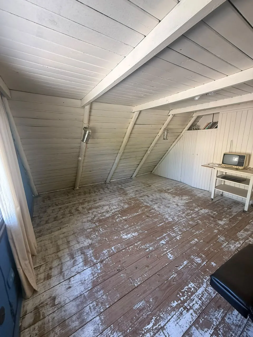 Segundo dormitorio de planta alta, tipo altillo: techo de madera a la vista, ventana y guardado bajo la pendiente