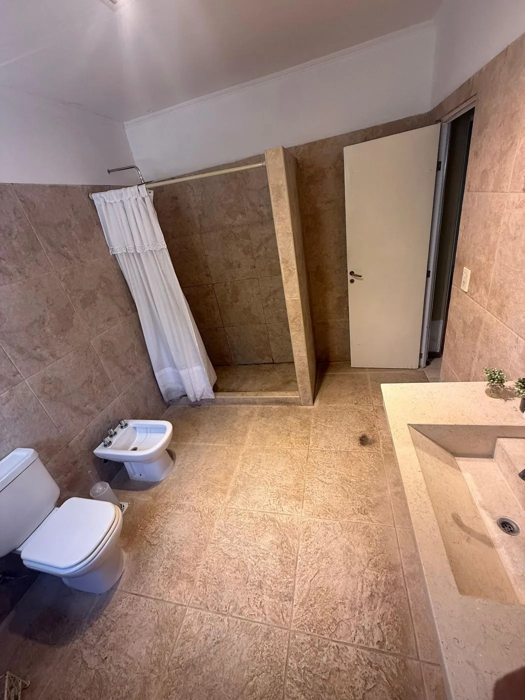 El mismo baño desde el otro lado: la ducha, el bidet y la bacha de mármol