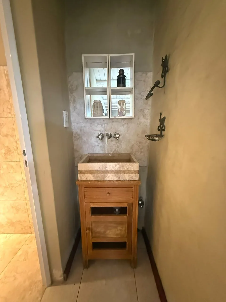 Toilette con bacha de piedra sobre mueble de madera y botiquín con espejo