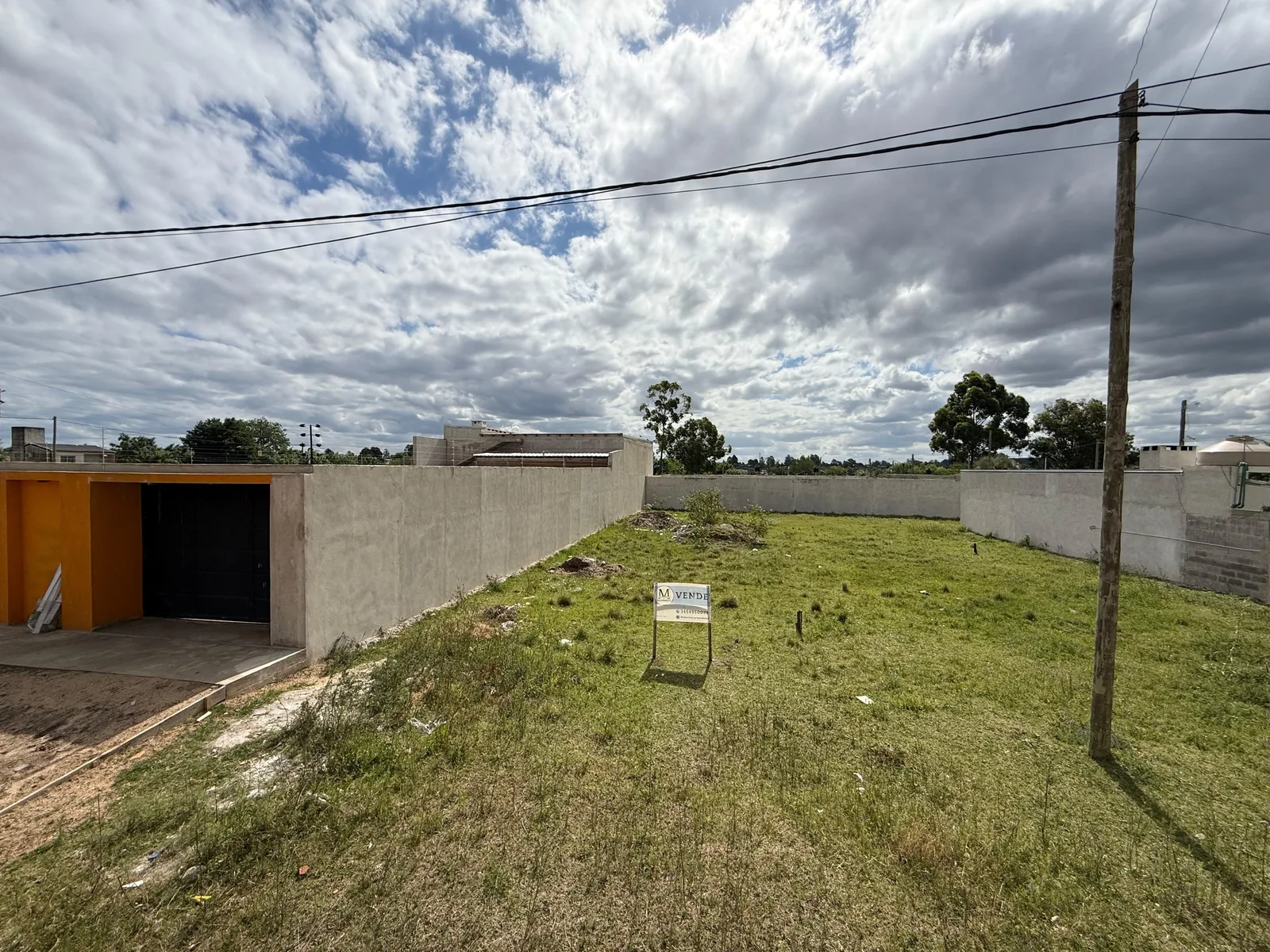 Lote sobre calle Chile, con el cartel de venta y los muros linderos