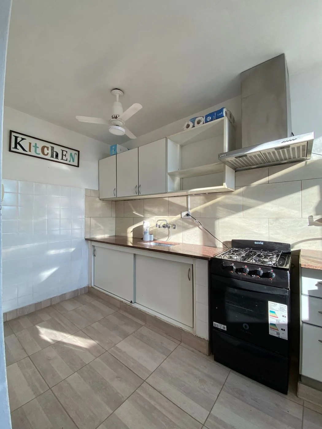 Cocina con extractor de acero, muebles bajo y sobre mesada y cocina con horno a gas natural