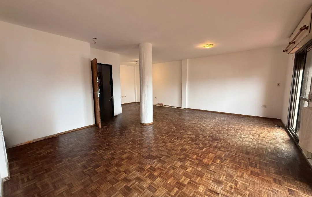 El living comedor, con piso de parquet, desde la puerta de entrada hasta las ventanas al balcón