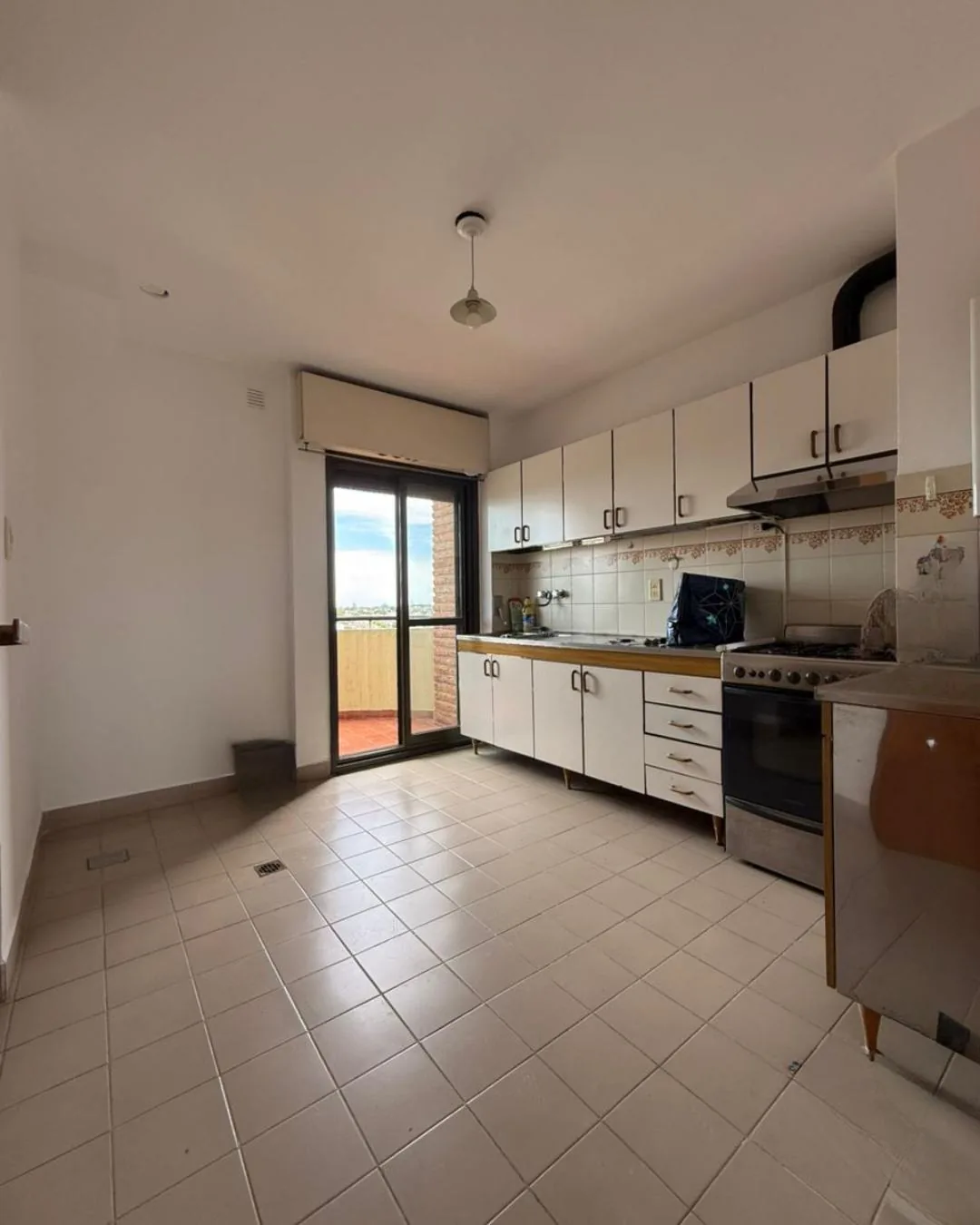 Cocina amplia con muebles bajo y sobre mesada, espacio para el comedor diario y salida propia al balcón