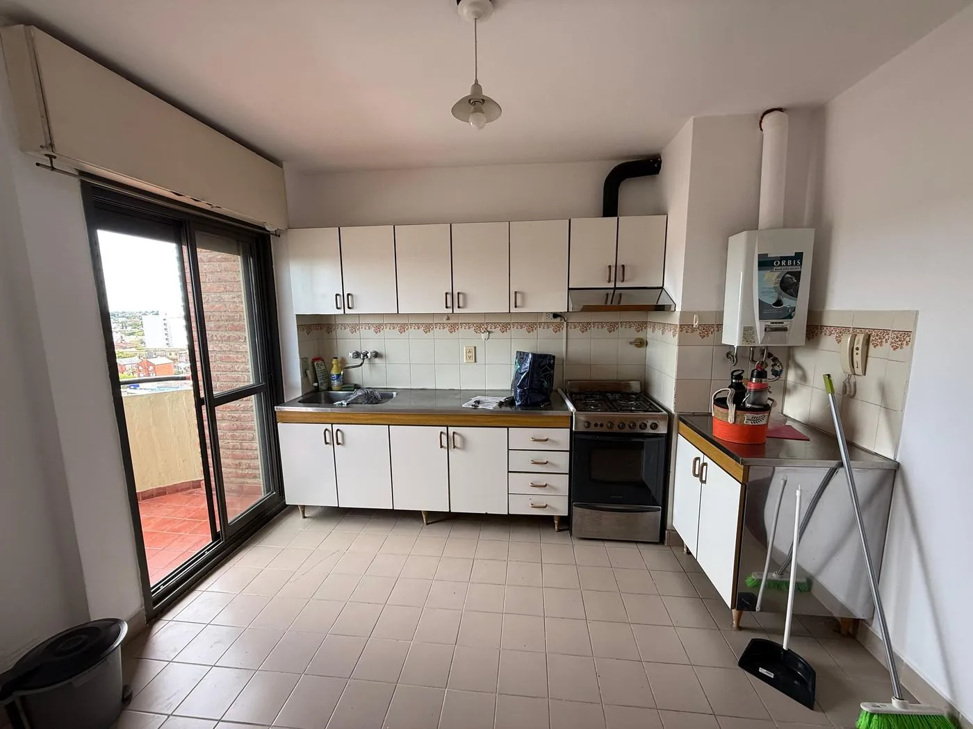 La cocina completa: mesada de acero inoxidable, cocina, campana y calefón a gas