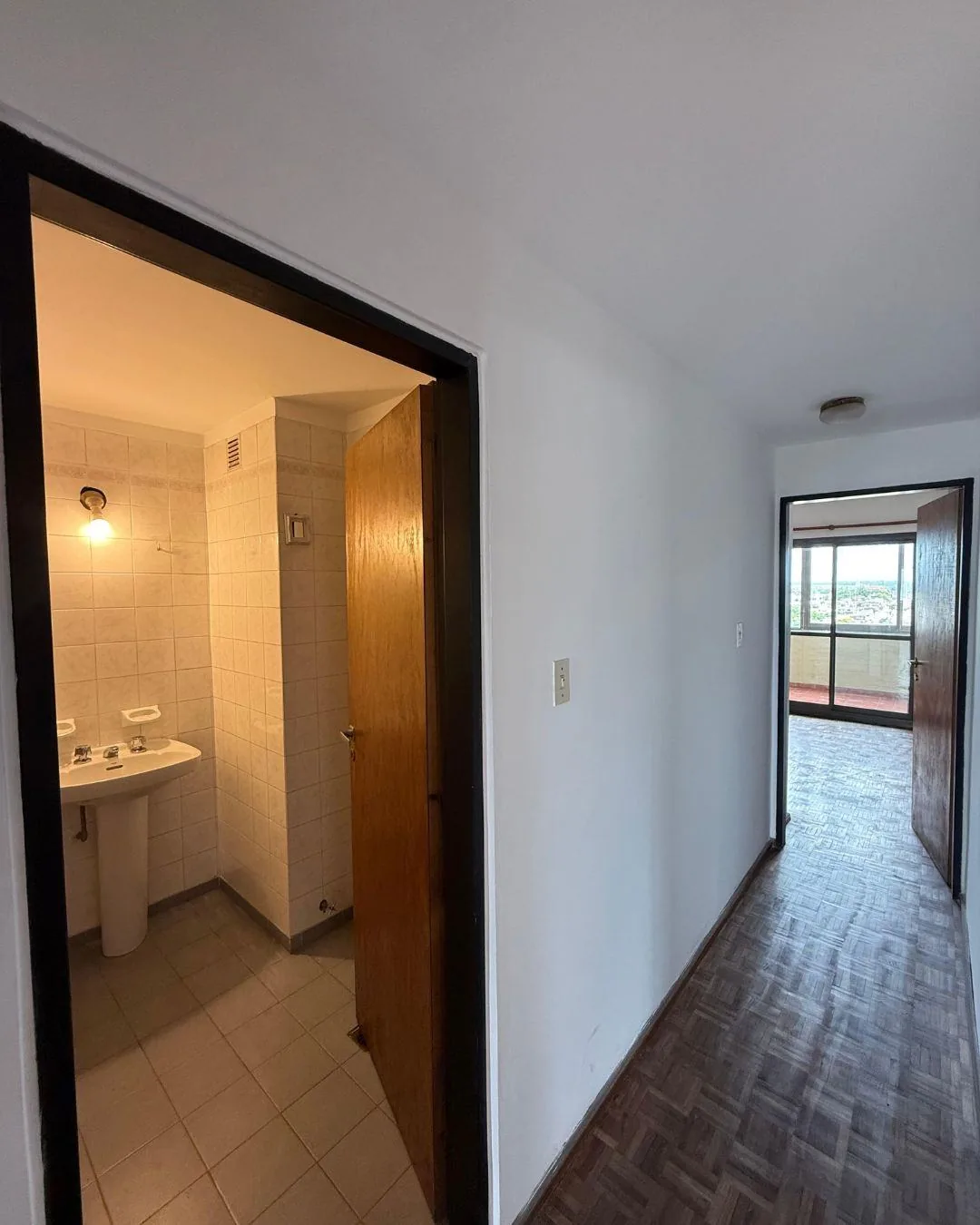 El pasillo del sector íntimo: el baño completo a la izquierda y el dormitorio principal al fondo, con salida al balcón