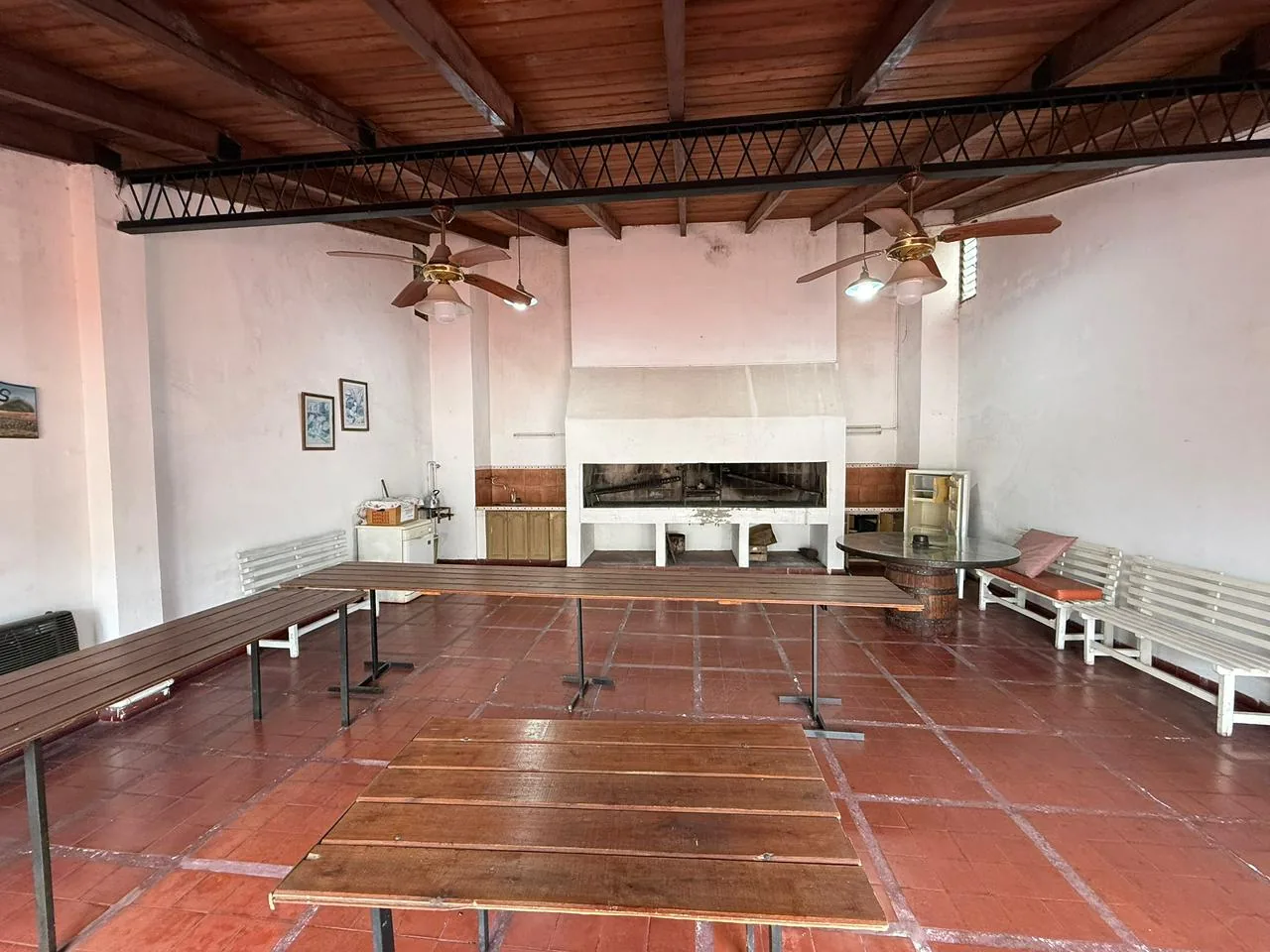 El quincho / SUM del edificio: parrilla de obra, mesada con bacha, ventiladores de techo y lugar para reuniones grandes