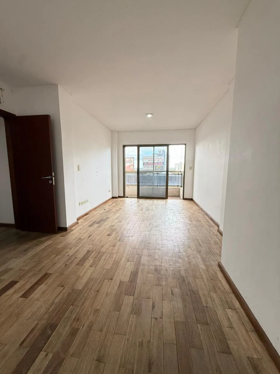 El living comedor de frente al balcón, con la puerta corrediza de aluminio y persiana eléctrica