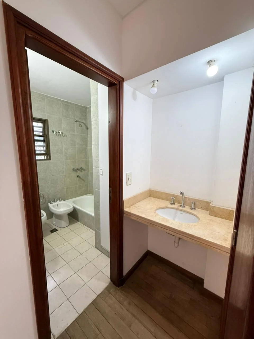 El antebaño con mesada de mármol y, al lado, el baño en suite completo con bañera y bidet