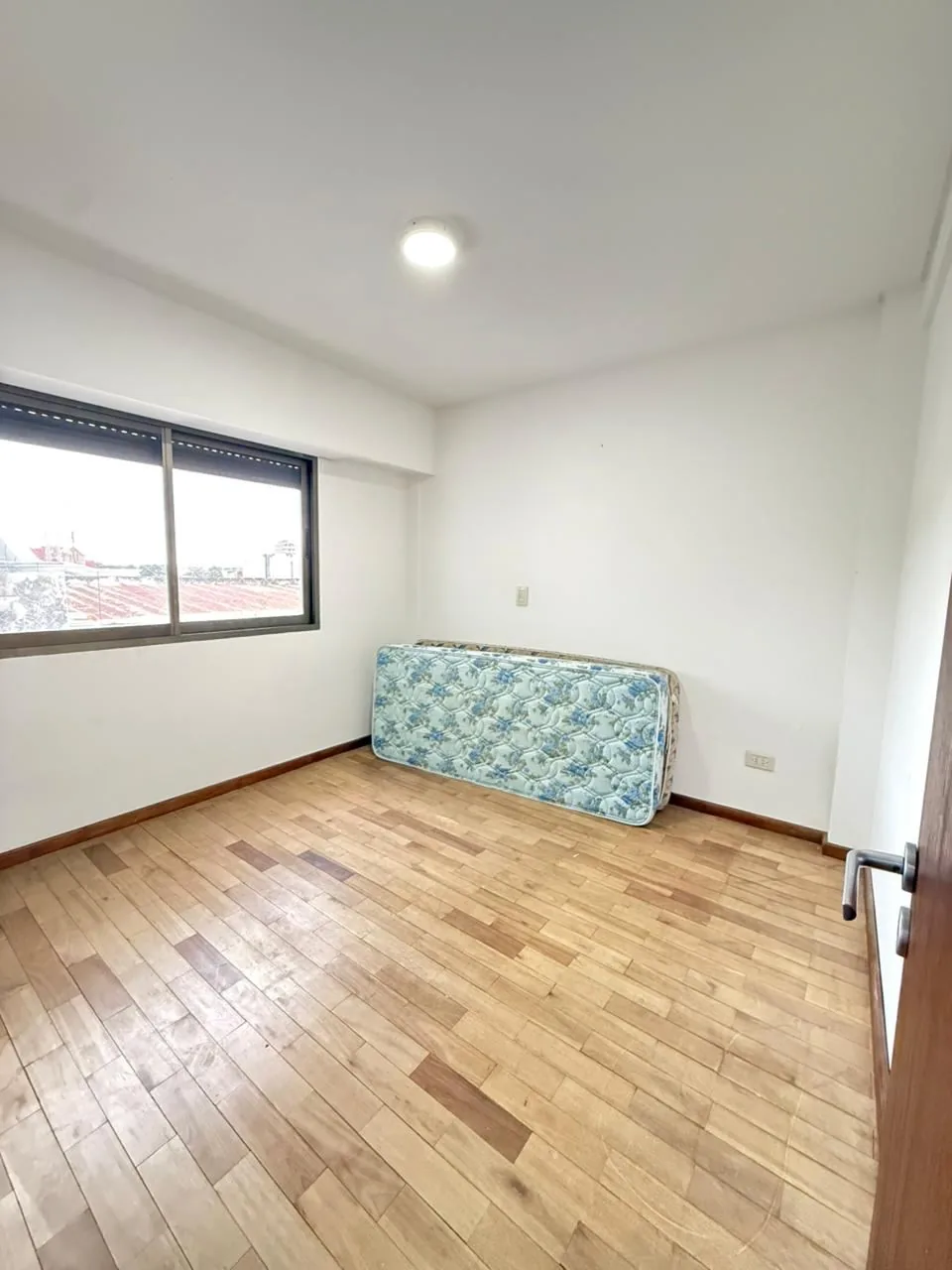 Otra vista del tercer dormitorio, con la ventana y el piso de madera