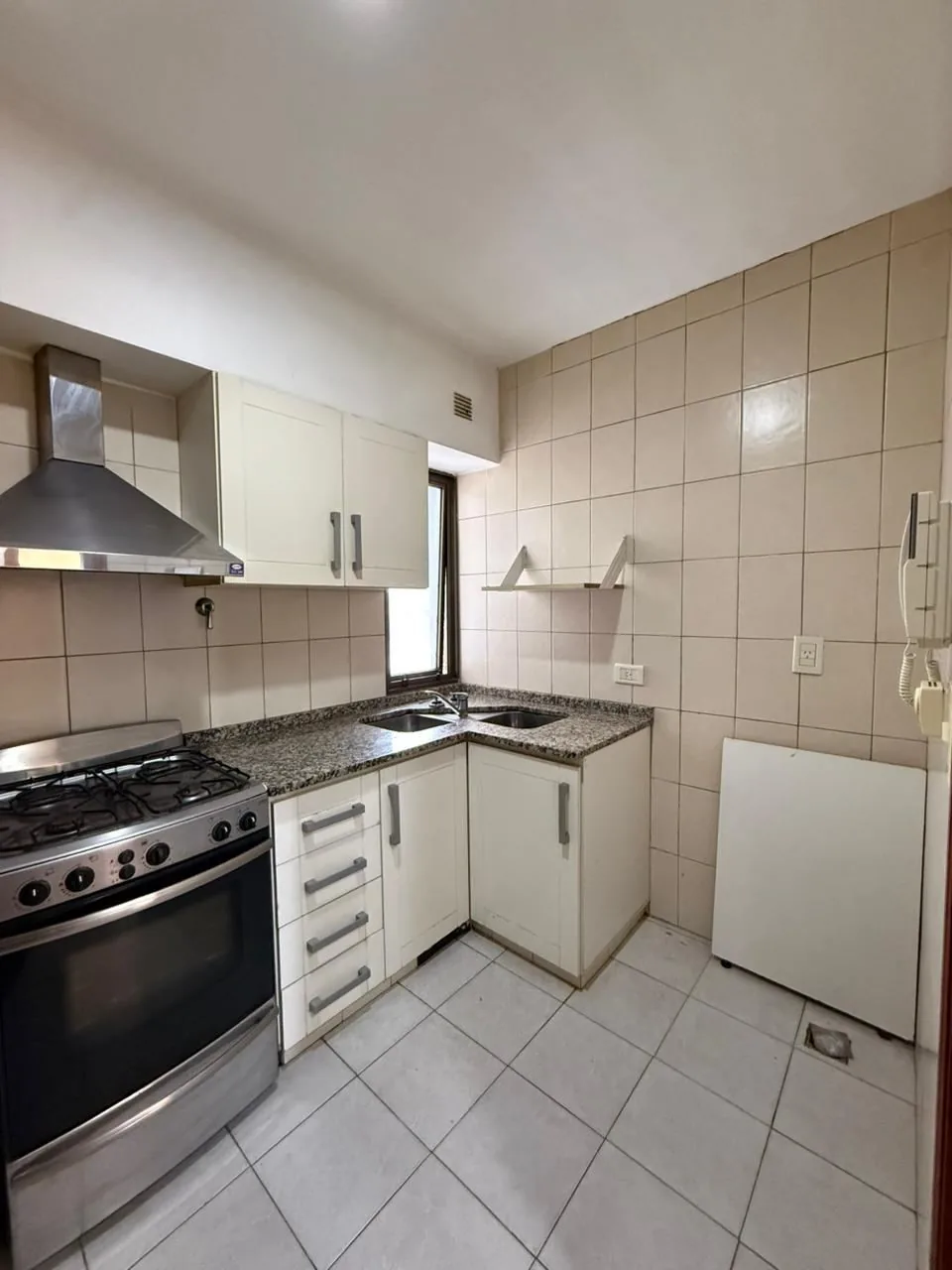 La cocina con horno, campana de acero, alacenas y portero eléctrico